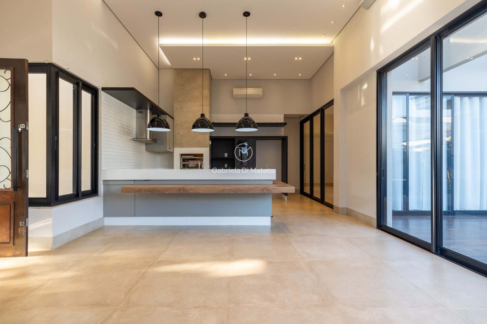 Espaço gourmet com ilha, iluminação pendente e integração com a sala de jantar